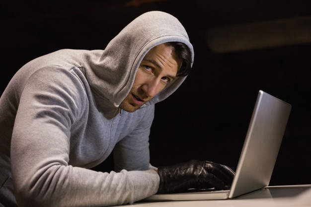 man-hood-jacket-hacking-laptop-while-looking-camera_13339-279164